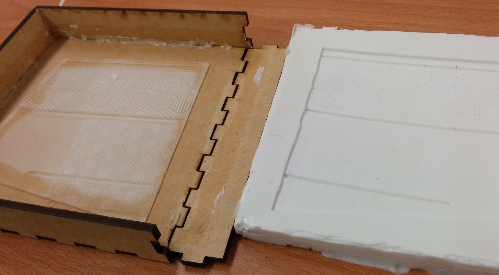 Laser cut box with an acrlyic positive next to a cast silicone mold made from that box