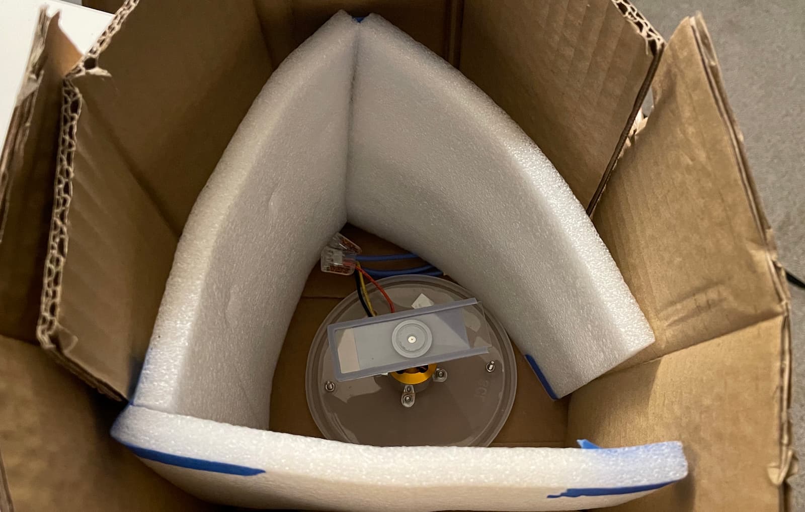 A spin coater surrounded by foam and two layers of cardboard boxes